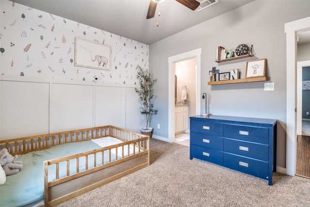 carpeted bedroom with wallpapered walls, visible vents, connected bathroom, wainscoting, and ceiling fan