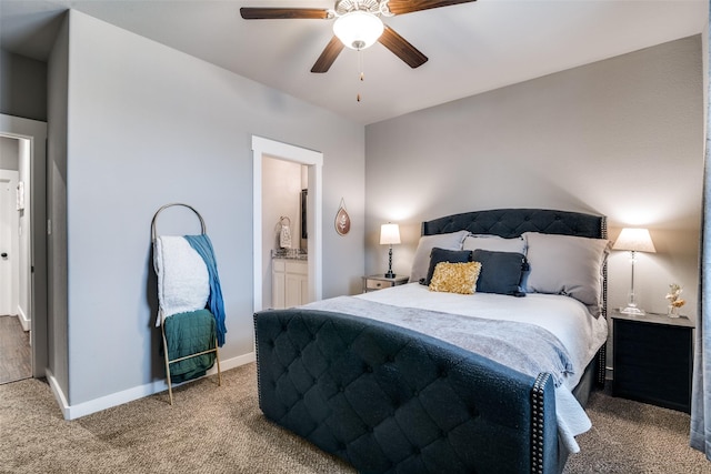 carpeted bedroom featuring a ceiling fan, ensuite bath, and baseboards