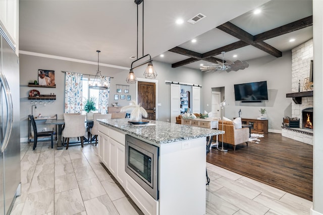 kitchen featuring visible vents, a barn door, white cabinets, built in appliances, and coffered ceiling