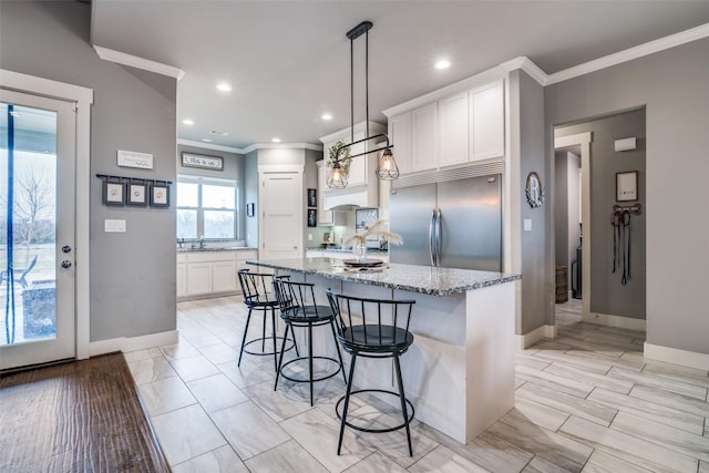 kitchen featuring white cabinets, light stone counters, a breakfast bar area, stainless steel built in fridge, and crown molding