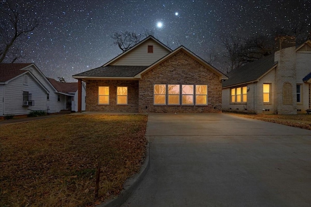 view of front of property featuring brick siding, cooling unit, and a front yard