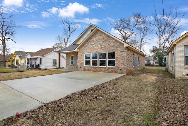 exterior space featuring brick siding, a lawn, and a patio area