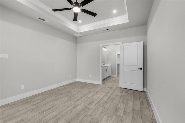 unfurnished bedroom with light wood finished floors, baseboards, visible vents, a raised ceiling, and ornamental molding