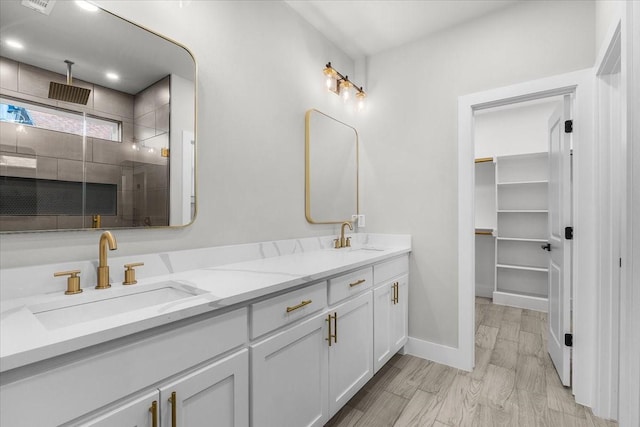 bathroom with wood finished floors, a sink, a shower stall, and double vanity