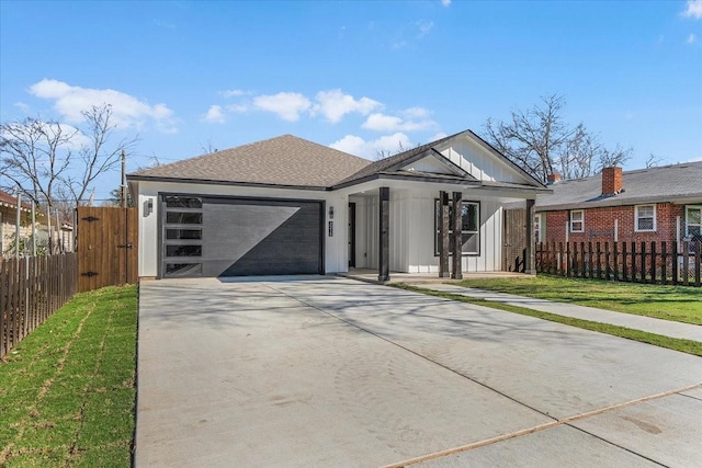 view of front of property featuring a garage, concrete driveway, fence, board and batten siding, and a front yard