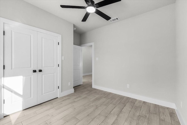 unfurnished bedroom featuring light wood-style floors, a closet, visible vents, and baseboards