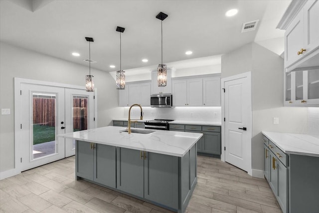 kitchen with visible vents, decorative backsplash, appliances with stainless steel finishes, gray cabinets, and a sink