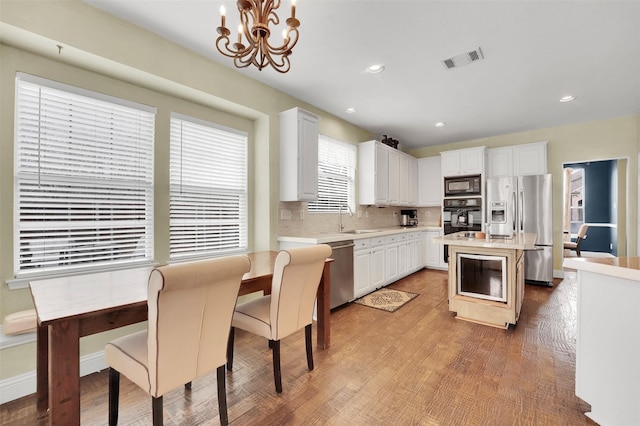 kitchen featuring light countertops, visible vents, decorative backsplash, a chandelier, and black appliances