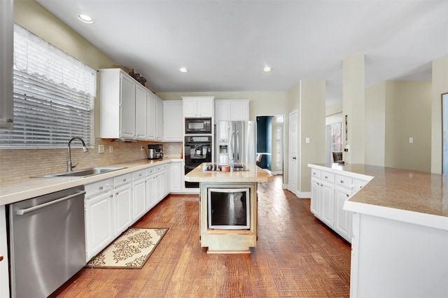 kitchen with decorative backsplash, a kitchen island, light countertops, black appliances, and a sink