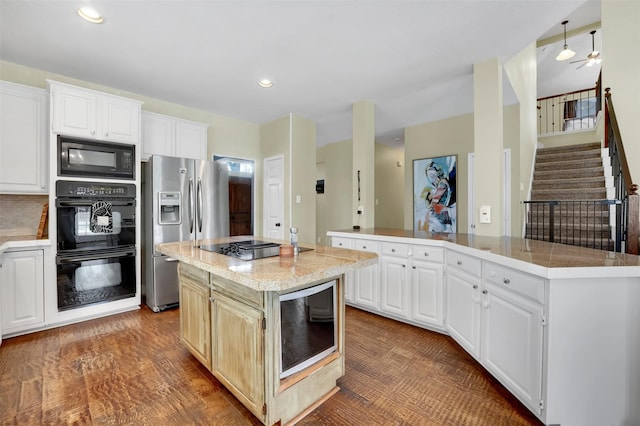 kitchen with a kitchen island, wood finished floors, white cabinets, decorative backsplash, and black appliances