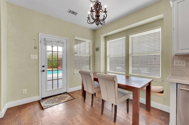 dining room with baseboards, wood finished floors, visible vents, and an inviting chandelier