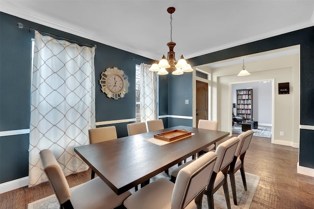 dining room featuring visible vents, an accent wall, ornamental molding, wood finished floors, and baseboards