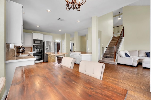 kitchen featuring visible vents, an inviting chandelier, light countertops, black appliances, and a sink