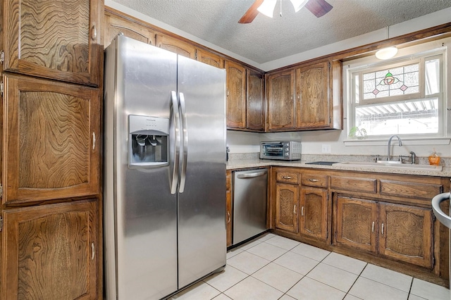 kitchen with stainless steel appliances, light countertops, a sink, and light tile patterned flooring