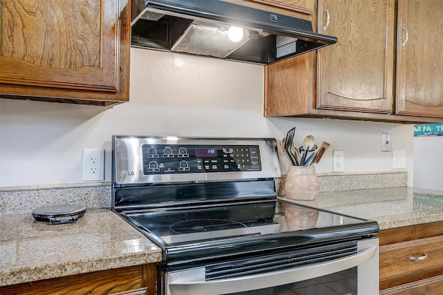 kitchen featuring under cabinet range hood, stainless steel electric range, and brown cabinets