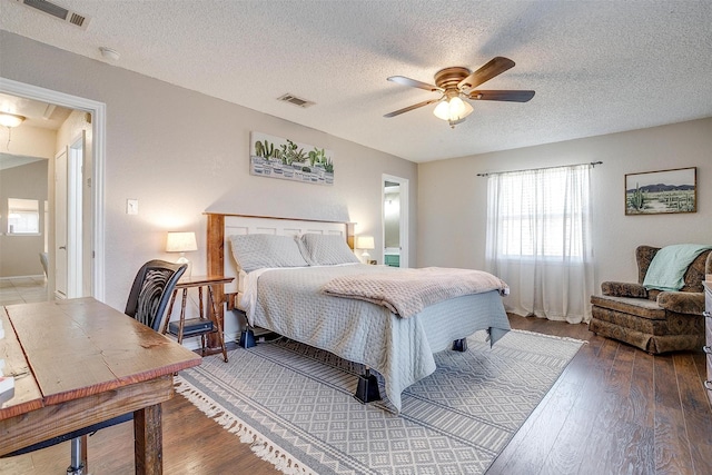 bedroom featuring attic access, visible vents, a textured ceiling, and hardwood / wood-style flooring