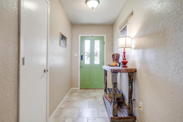 doorway featuring stone finish flooring, a textured wall, a textured ceiling, and baseboards