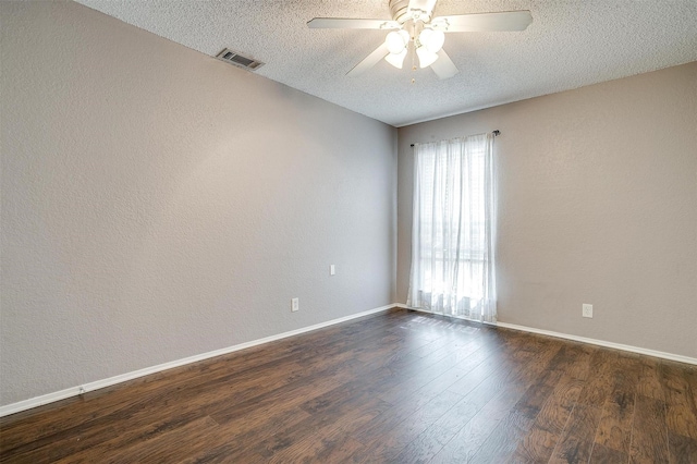 unfurnished room featuring baseboards, visible vents, dark wood finished floors, and a textured ceiling