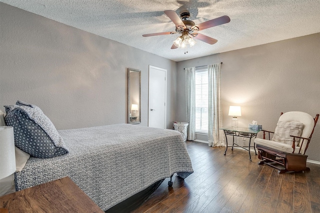 bedroom featuring baseboards, a textured wall, ceiling fan, hardwood / wood-style floors, and a textured ceiling