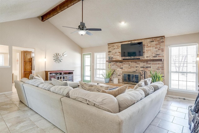 living area with a textured ceiling, a wealth of natural light, a brick fireplace, and beam ceiling