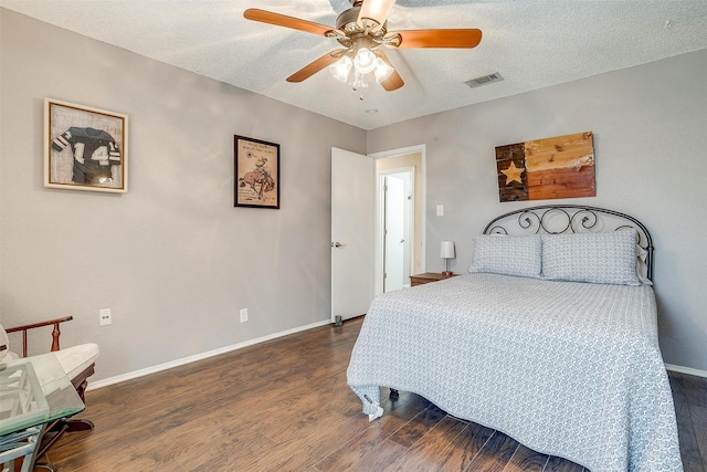 bedroom featuring visible vents, a textured ceiling, baseboards, and wood finished floors