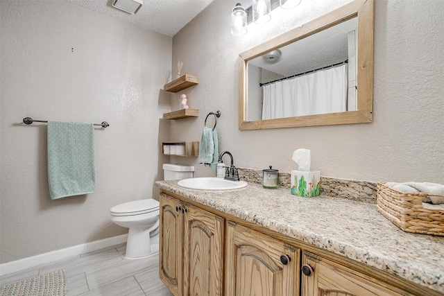 full bath featuring baseboards, a textured wall, toilet, a textured ceiling, and vanity