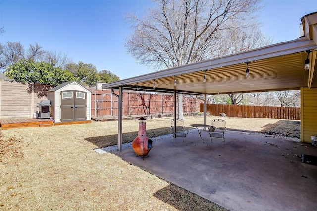 view of patio featuring a storage shed, grilling area, an outdoor structure, and a fenced backyard