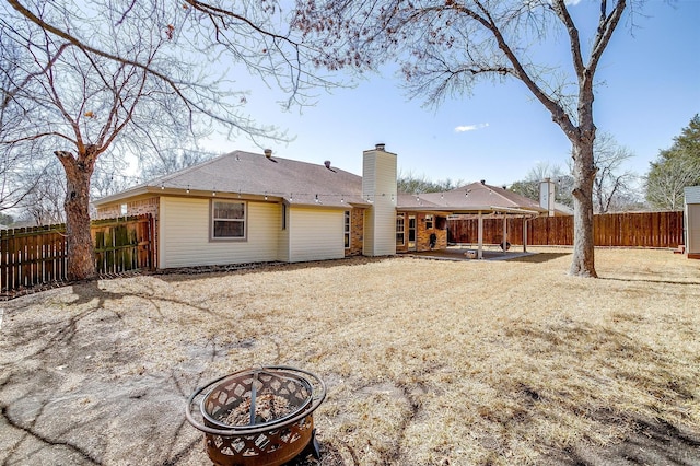 back of property featuring a patio, brick siding, a chimney, and a fenced backyard