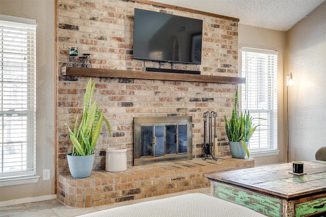 living area featuring tile patterned flooring, a fireplace, baseboards, and a textured ceiling