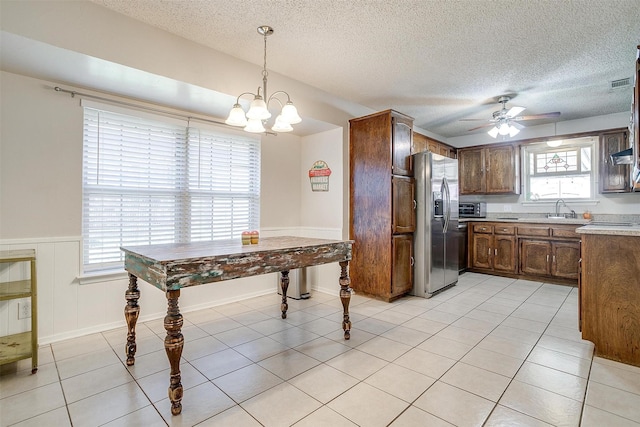 kitchen featuring pendant lighting, light countertops, light tile patterned flooring, a sink, and stainless steel fridge with ice dispenser