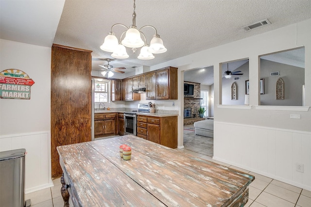 kitchen featuring a wainscoted wall, stainless steel electric range, visible vents, and a sink