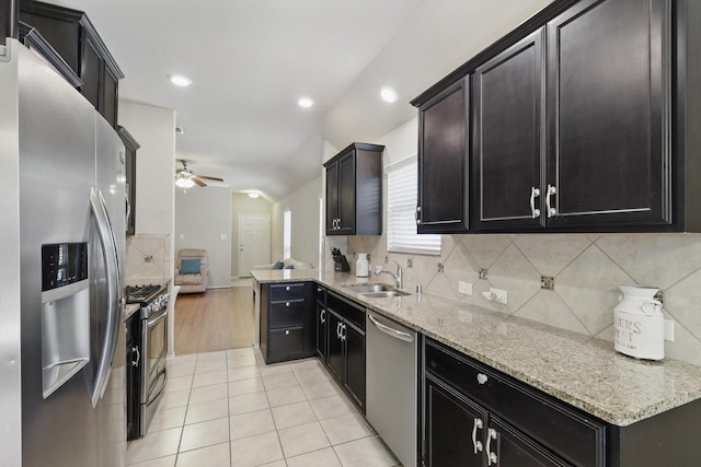 kitchen featuring light tile patterned floors, ceiling fan, light stone counters, a sink, and appliances with stainless steel finishes