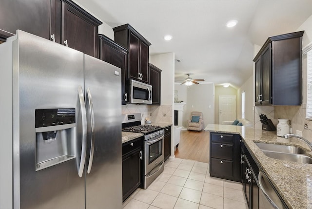 kitchen featuring stainless steel appliances, light tile patterned flooring, a sink, and light stone countertops