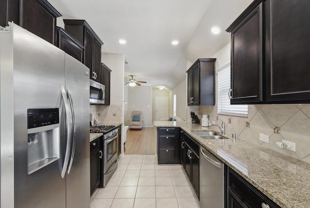 kitchen with light tile patterned floors, appliances with stainless steel finishes, a sink, ceiling fan, and light stone countertops