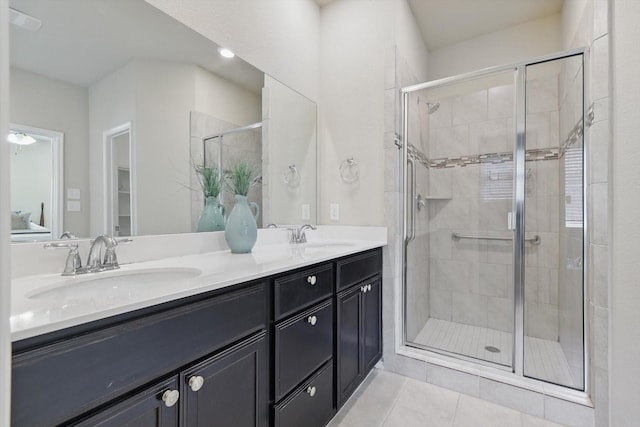 full bath featuring double vanity, a sink, a shower stall, and tile patterned floors