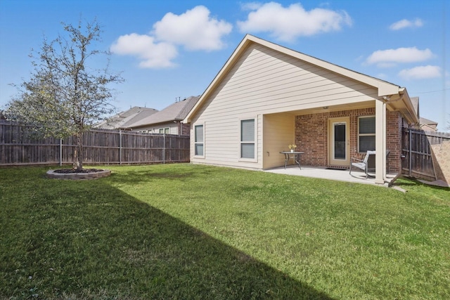 back of house featuring a yard, a fenced backyard, a patio, and brick siding