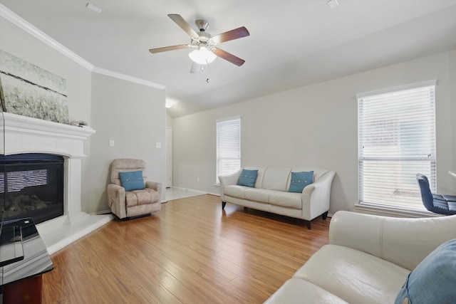 living room featuring crown molding, lofted ceiling, a ceiling fan, a glass covered fireplace, and wood finished floors