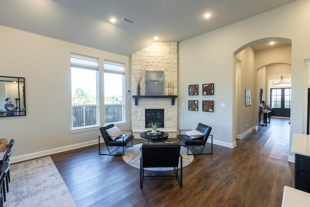 living area featuring visible vents, arched walkways, dark wood-style floors, and a fireplace