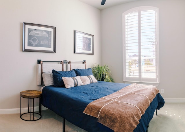 carpeted bedroom featuring baseboards, multiple windows, and ceiling fan