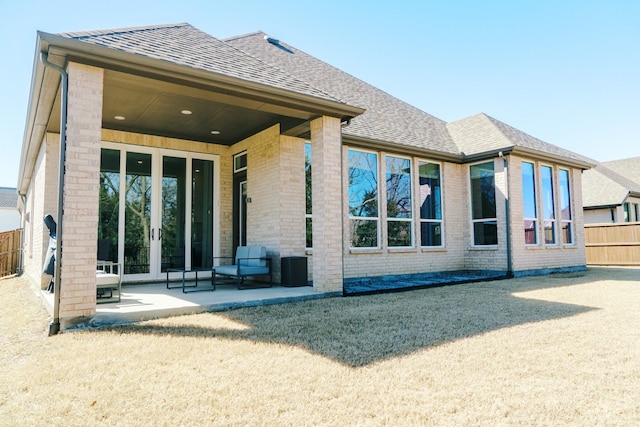 back of house featuring brick siding, a shingled roof, a patio, and fence