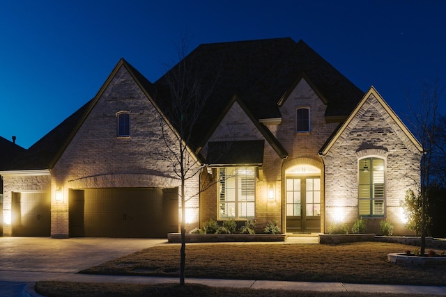 french country home with french doors, brick siding, and concrete driveway