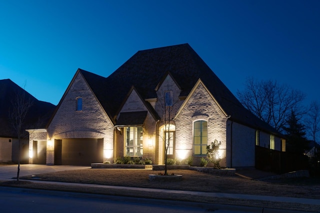 french provincial home featuring stone siding, brick siding, and concrete driveway