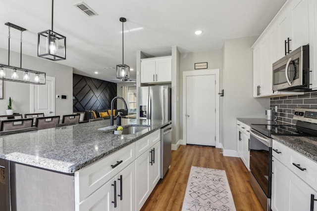 kitchen featuring visible vents, decorative backsplash, appliances with stainless steel finishes, a sink, and wood finished floors