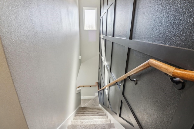 staircase featuring a textured wall and baseboards