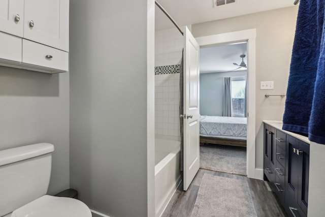 ensuite bathroom with shower / bathtub combination, visible vents, toilet, ensuite bath, and wood finished floors