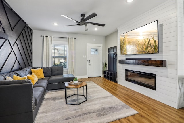 living room featuring recessed lighting, a large fireplace, baseboards, and wood finished floors