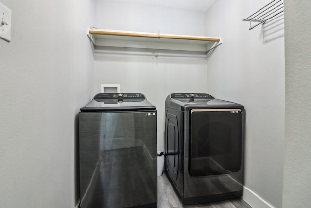 clothes washing area featuring baseboards, laundry area, light wood-style flooring, and washer and dryer