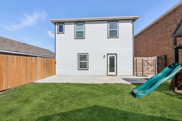 rear view of house with a playground, a lawn, a patio area, and a fenced backyard