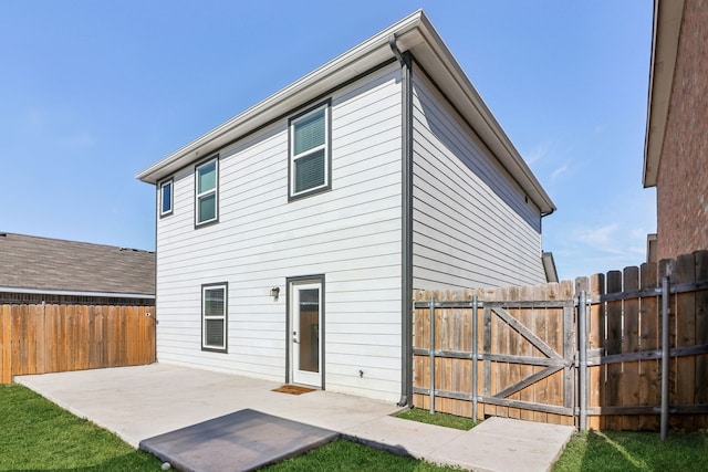 back of house featuring a patio area, a gate, fence, and a yard