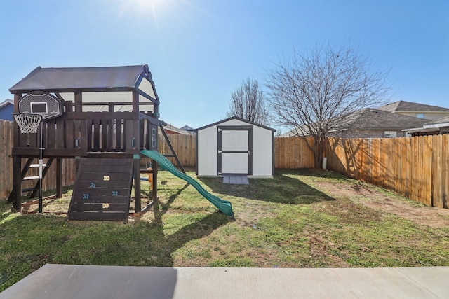 view of playground featuring a yard, a shed, an outdoor structure, and a fenced backyard